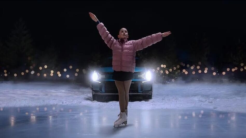 Super Bowl ad scene: a young skater performs on a frozen pond lit by an electric SUV's headlights